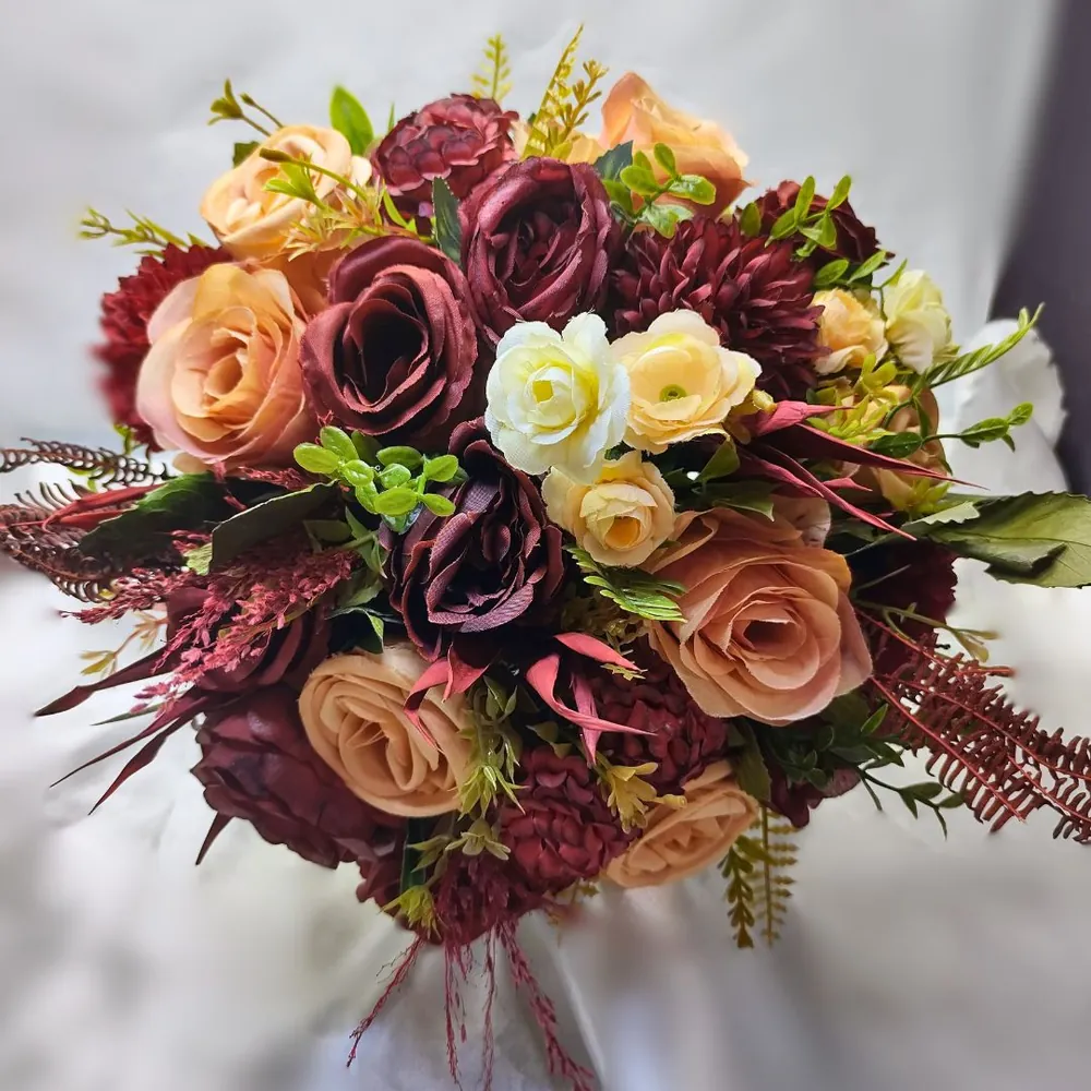 Buquê de rosas em tons de vinho, salmão e creme, com folhagens e detalhes delicados