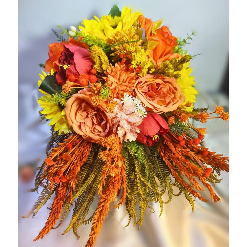 Buquê cascata semirrealista com girassóis, rosas cor de pêssego, peônias e capim seco em tons terracota