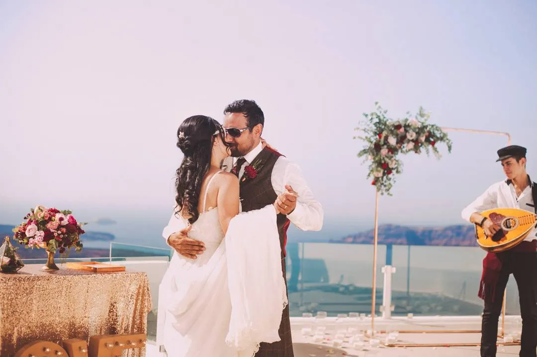 Noivos dançando em um casamento ao ar livre, com um músico tocando por perto