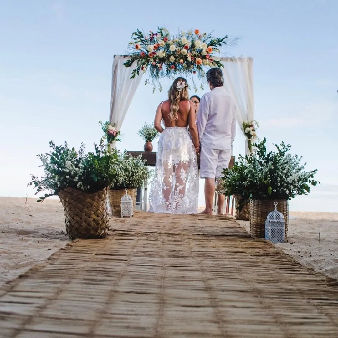 Noivo e noiva durante a cerimônia de casamento na praia, com o mar ao fundo