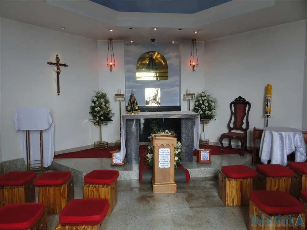Interior da Capela Nossa Senhora Aparecida no Santuário Cristo Redentor, com altar, crucifixo e bancos vermelhos