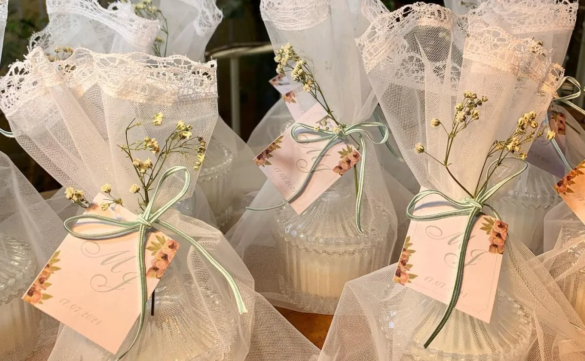 Lembrancinhas de casamento embrulhadas em tule, com fita verde e pequenas flores