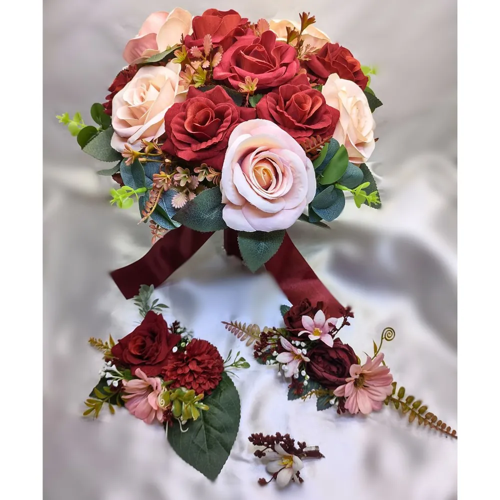 Buquê de noiva com rosas vermelhas, rosas rosadas e laço vinho, acompanhado de lapelas florais para o noivo e padrinhos