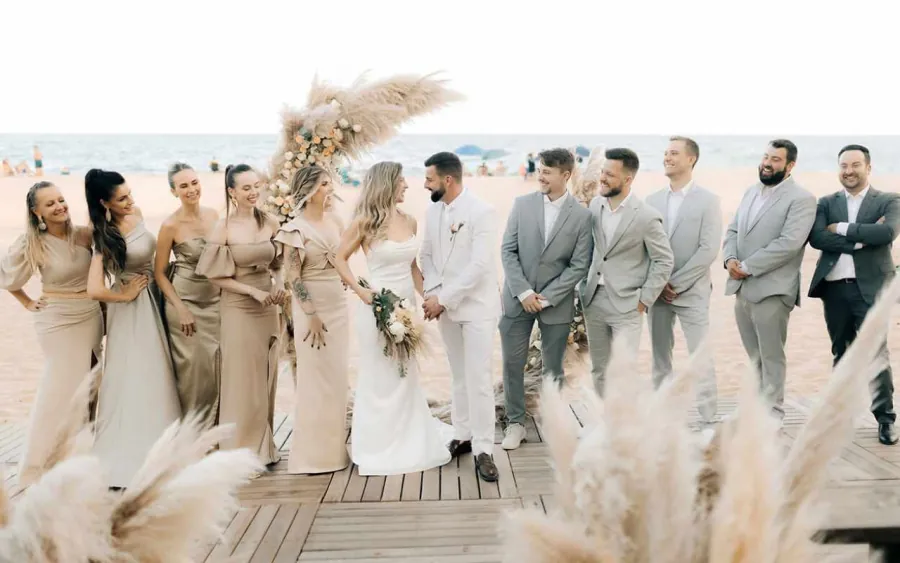 Grupo de padrinhos e madrinhas ao lado dos noivos em uma cerimônia de casamento na praia