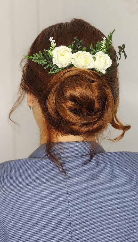 Arranjo de cabelo de noiva com rosas brancas e folhagens em coque baixo